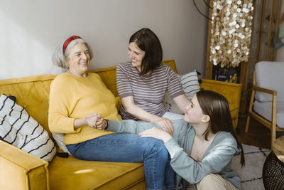 Portrait of smiling friends sitting on sofa at home