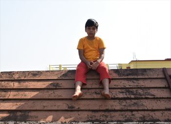 Full length of boy standing on staircase against clear sky