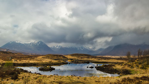 Scenic view of lake by mountains against sky