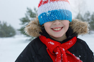 Happy boy in bright winter clothes and a red scarf