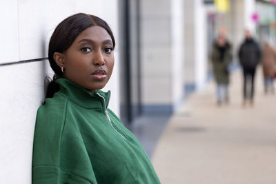 Portrait of young woman standing against building