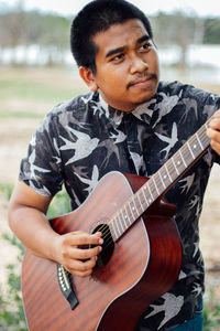 Portrait of young woman playing guitar