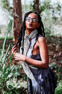 Portrait of young woman wearing eyeglasses standing against plants