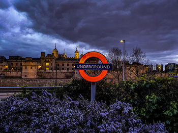 Information sign by building against sky at dusk