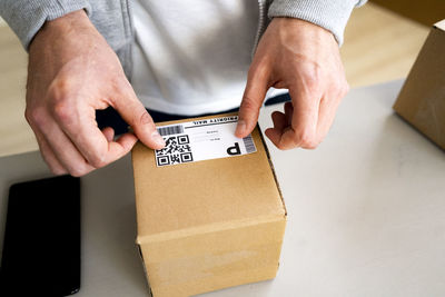 Businessman sticking bar code on cardboard box at desk