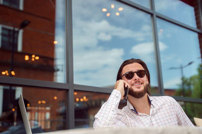 Smiling man talking on phone while sitting at cafe