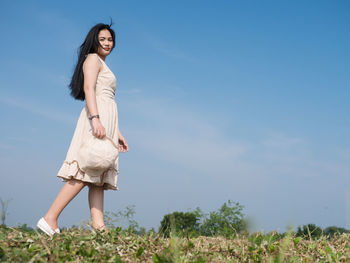 Low angle view of woman standing on field against sky