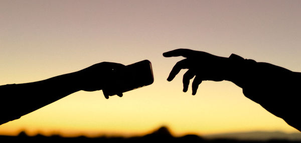 Low angle view of silhouette woman standing against clear sky during sunset