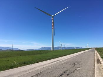 Wind turbines on field against sky