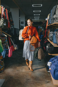 Full length of woman buying backpacks in shop