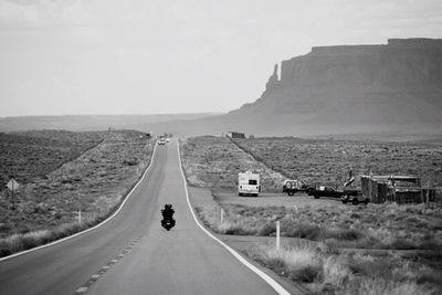 Road leading towards mountains against clear sky