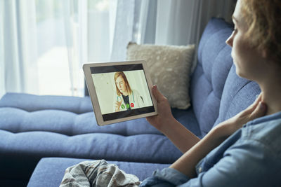 Woman using digital tablet while lying on bed at home