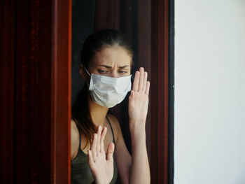 Portrait of young woman standing against door