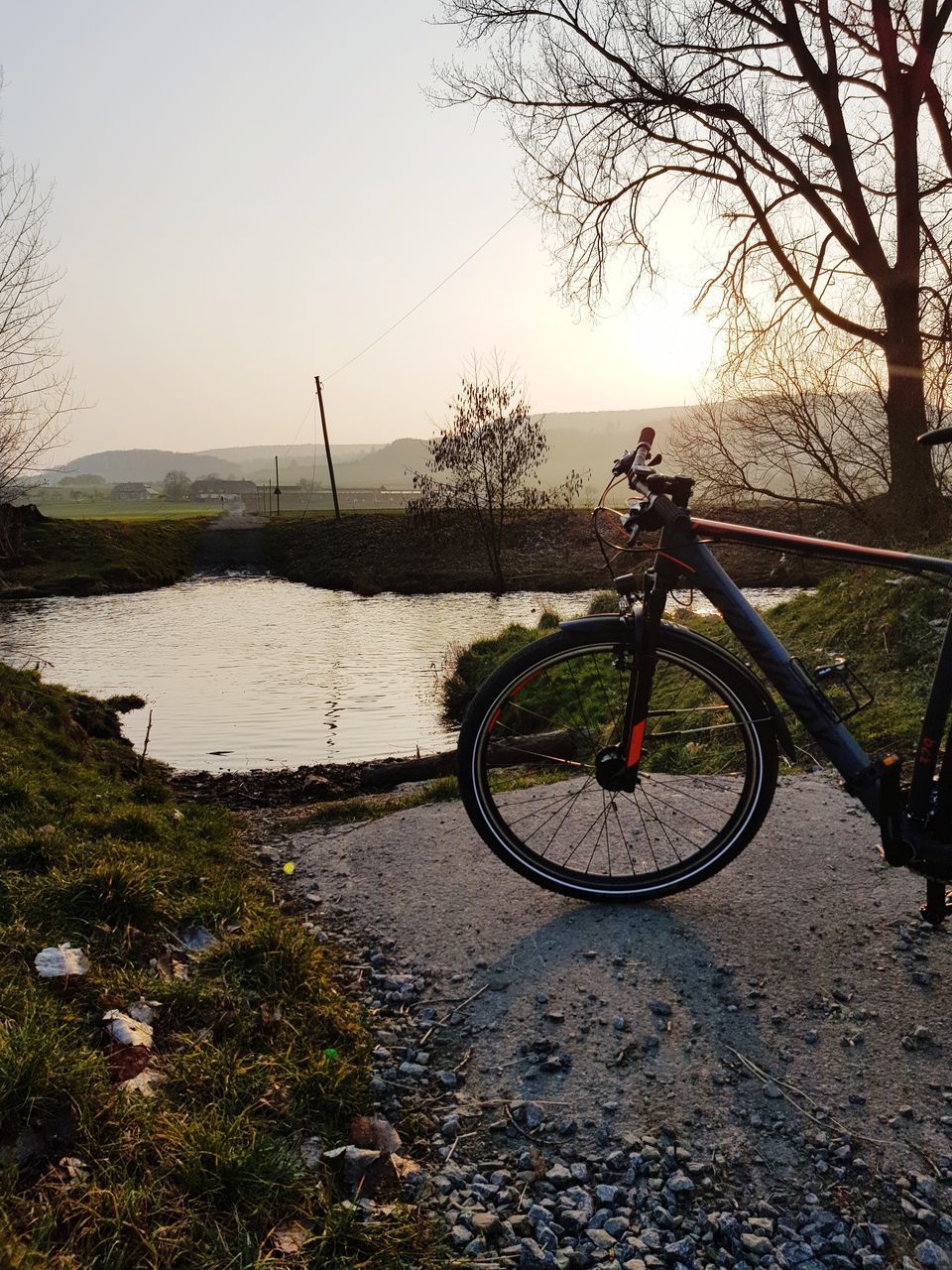 BICYCLE PARKED BY LAKE AGAINST SKY