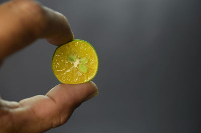 Close-up of hand holding apple against black background