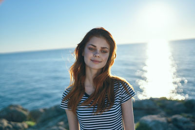 Portrait of beautiful young woman standing against sea