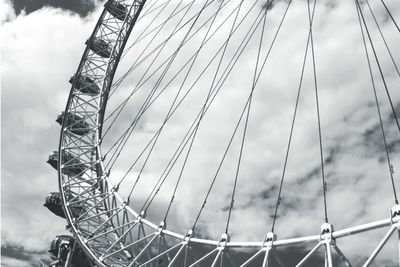 Cropped image of ferris wheel against cloudy sky