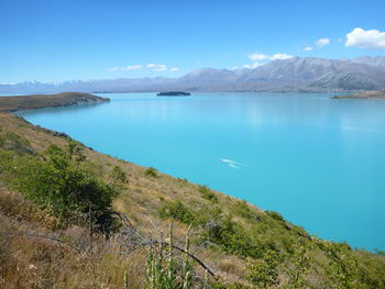 Scenic view of sea and mountains against blue sky