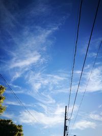 Low angle view of electricity pylon against blue sky