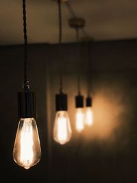 Close-up of illuminated light bulb hanging at home