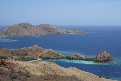 Scenic view of sea and mountains against clear blue sky