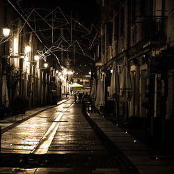 Illuminated street amidst buildings in city at night