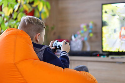 Young gamer boy playing online car racing game on new console at home tv