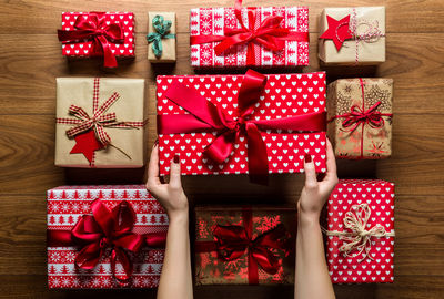 Cropped hands of woman arranging christmas presents on hardwood floor