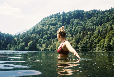 Woman standing in lake against trees