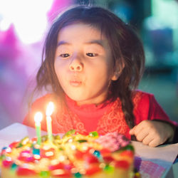 Close-up of happy girl with birthday cake on table