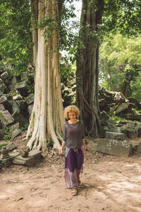 Full length woman walking against trees in forest