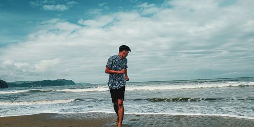 Full length of man standing on beach against sky