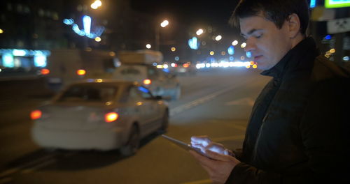 Man holding illuminated car on road at night