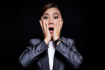 Portrait of surprised businesswoman against black background