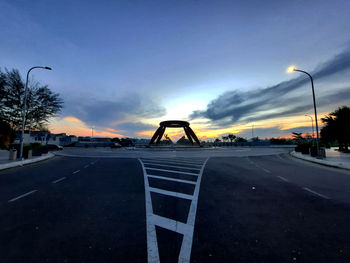 Empty road against sky at sunset