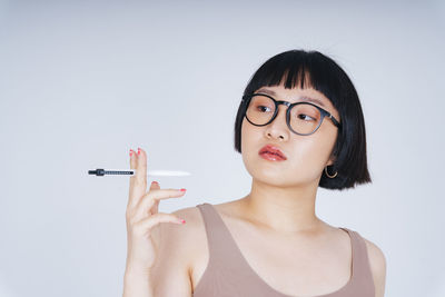 Young woman holding pen against white background