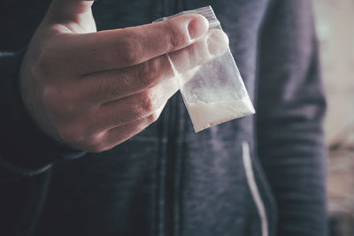 Midsection of man holding cocaine