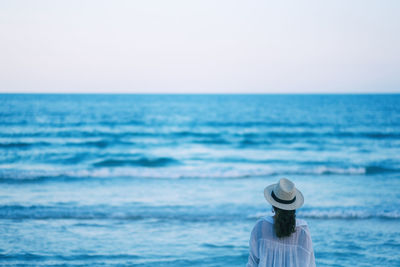 Rear view of woman looking away while standing by sea