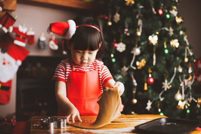 Girl making cookies at table during christmas