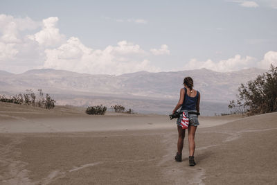 Rear view of woman walking on landscape against sky