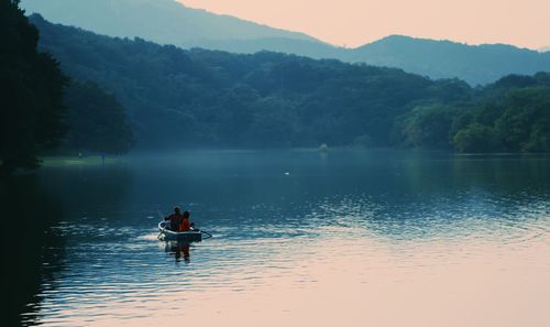 People in boat on lake against sky