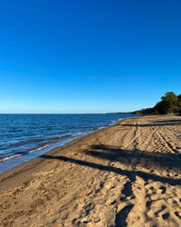 Scenic view of beach against clear blue sky