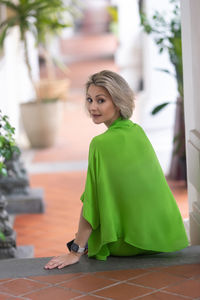 Caucasian blonde in bright green fashionable clothing poses in front of the camera.