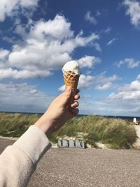 Midsection of person holding ice cream on beach