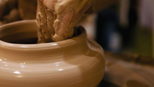 Cropped hands of potter making pot on pottery wheel