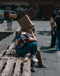 People sitting on footpath in city