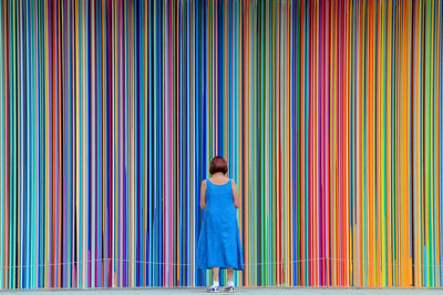 Full length of woman standing against colorful curtain