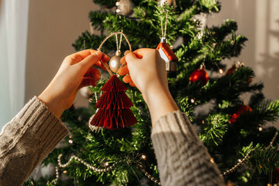 Close-up of the hands of a girl hanging a new year's toy on a christmas tree. eve of christmas 