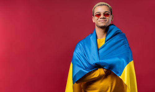 Portrait of young man standing against yellow background