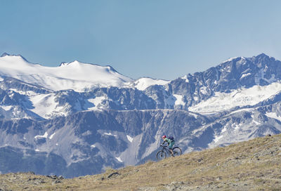 Man riding bicycle on mountain against sky